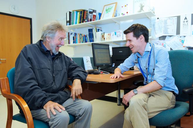 GP with elderly patient laughing