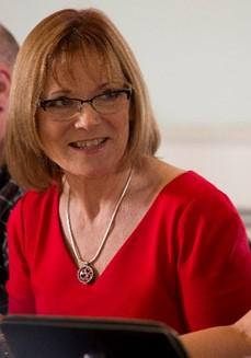 photo of a woman in a red top looking away from the camera and smiling