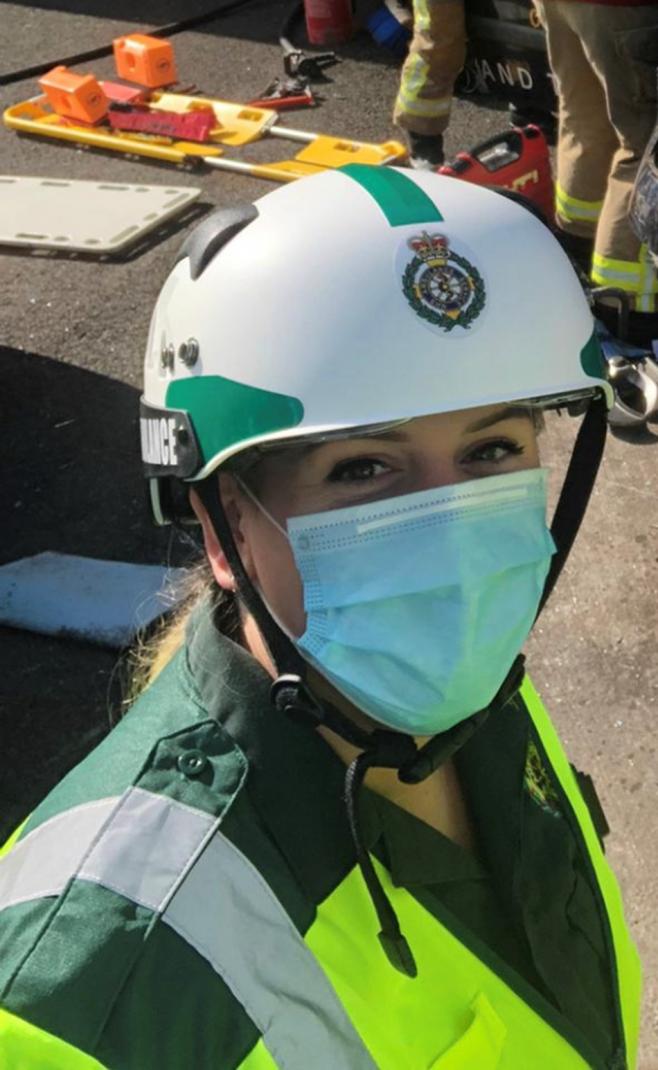 Lady looking at the camera wearing a white helmet, face mask and green jacket