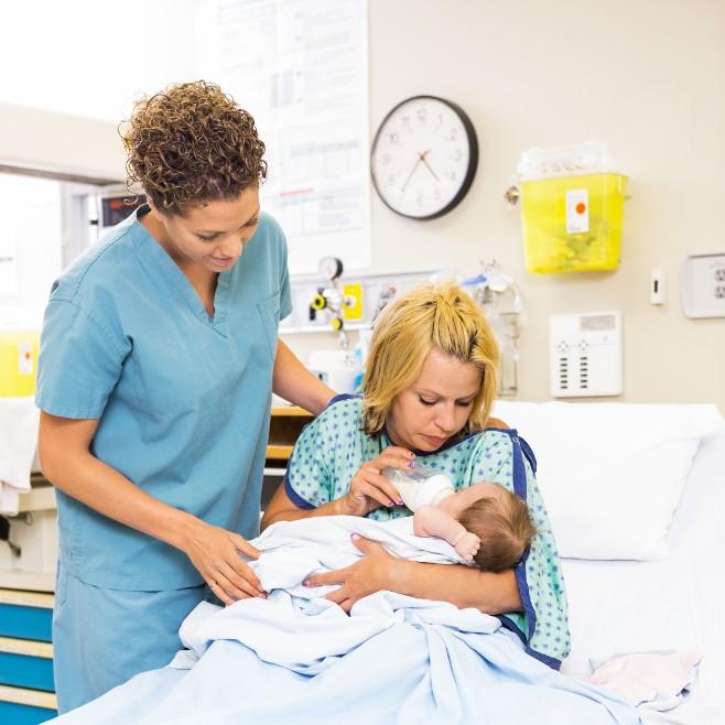 Midwife with a mother and baby in a maternity ward