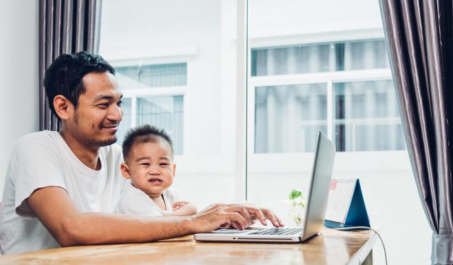 Man working on laptop with young child