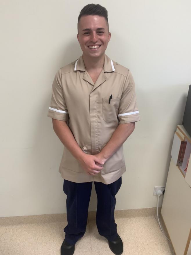 A man standing and smiling at the camera, dressed in his uniform.