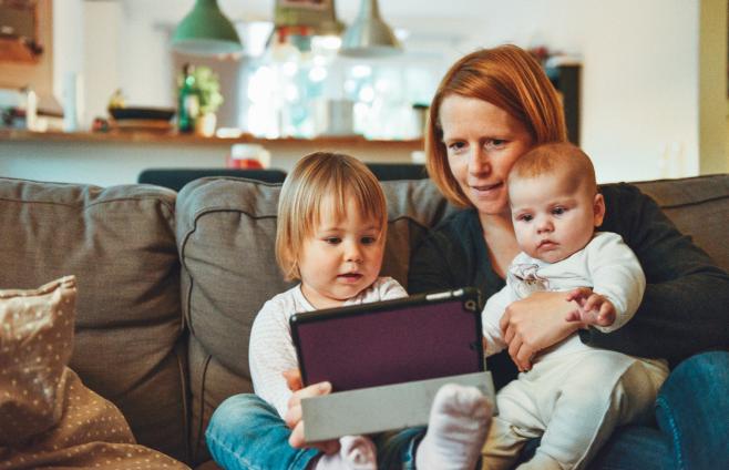 Woman with her young family while working on a tablet
