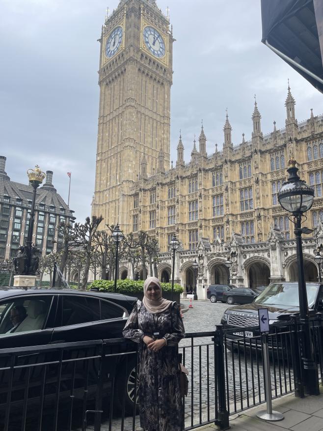 Picture of Zeenat Hassam outside the Houses of Parliament, with Big Ben in the background. 