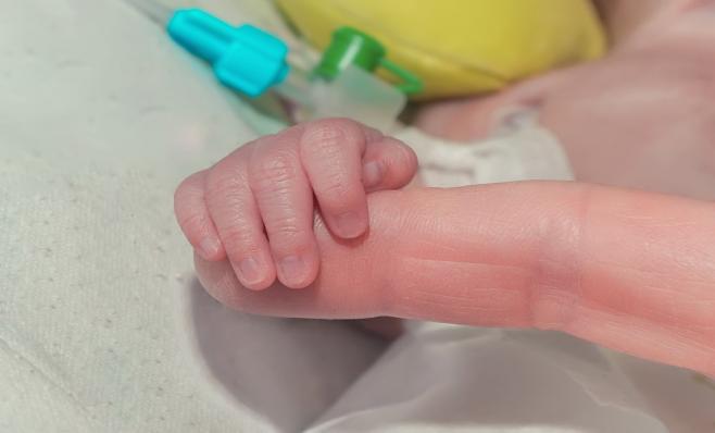 image of newborn baby holding an adult finger