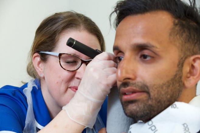 Female nurse looking in male's ear